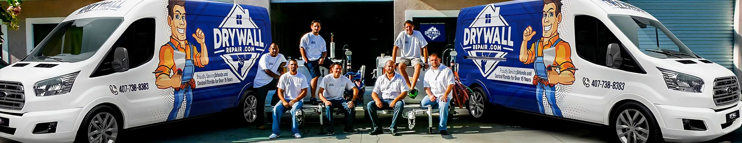 Drywall Repair team posing in front of branded service vans and garage.